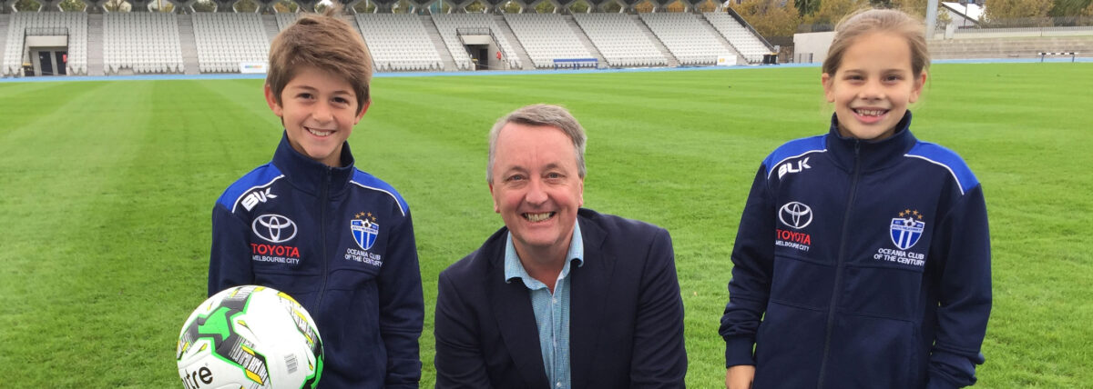 Martin Foley at a sports ground with two school students